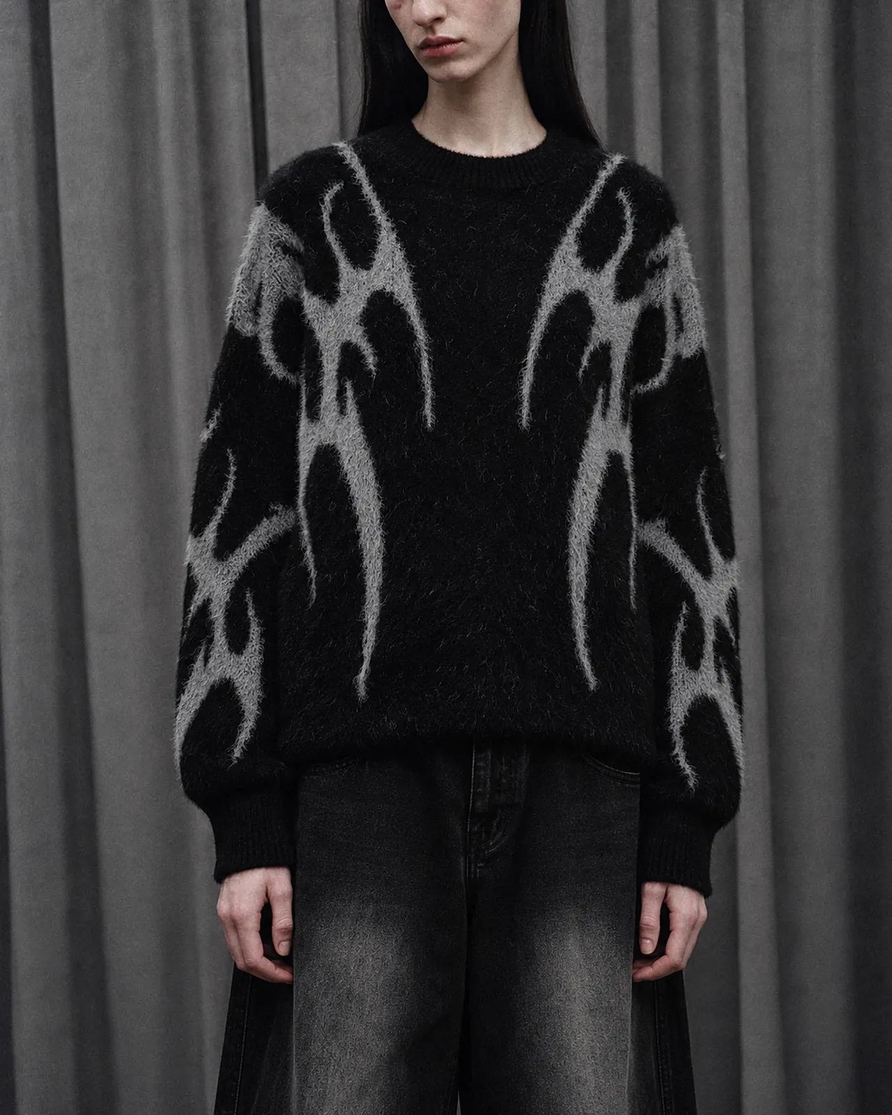 Close-up of The Dark Jacquard Knit Jumper: a grey flame pattern knitted into black yarn